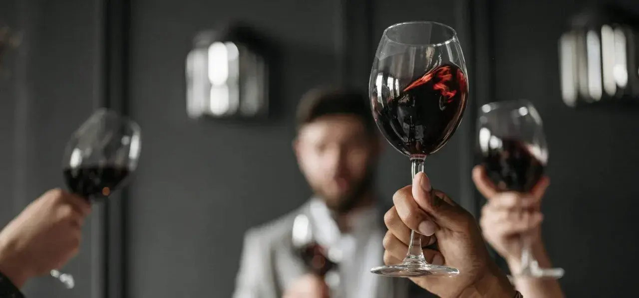 Verre de vin rouge, parfait pour accompagner un foie gras. Des mains lèvent des verres pour un toast.