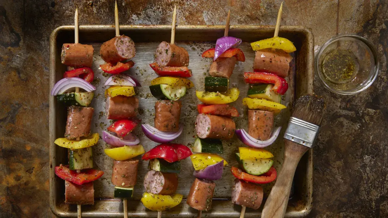 Spiedini di carne succulenti con peperoni, cipolle e zucchine, pronti per essere grigliati.