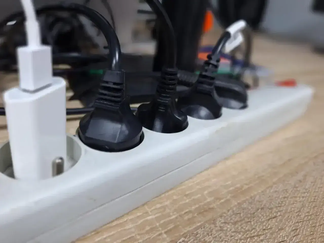 Wieloportowa listwa zasilająca z wieloma wtyczkami, w tym białą ładowarką USB, pokazuje potrzebę przedłużania przewodów elektrycznych.