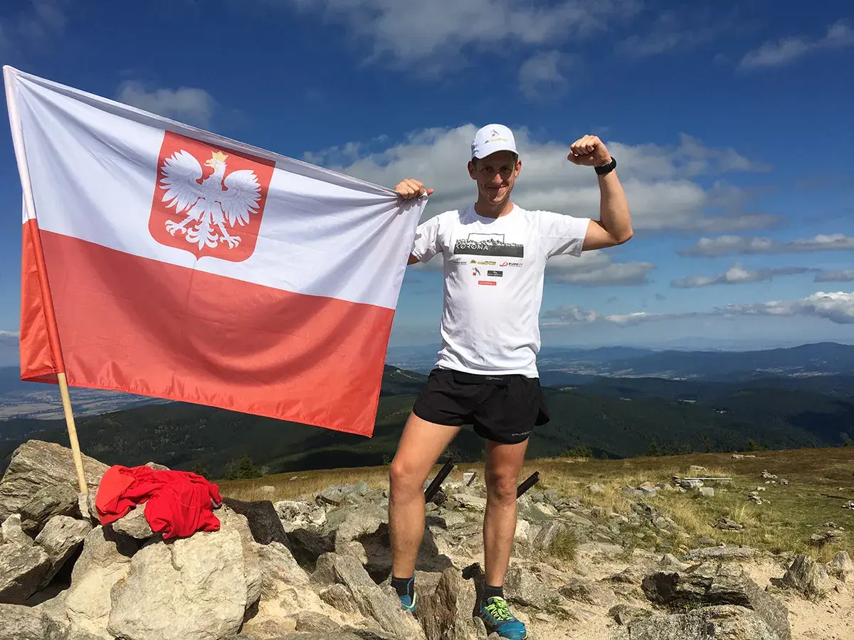 Zdobywca Korony Polskich Gór z biało-czerwoną flagą na szczycie.