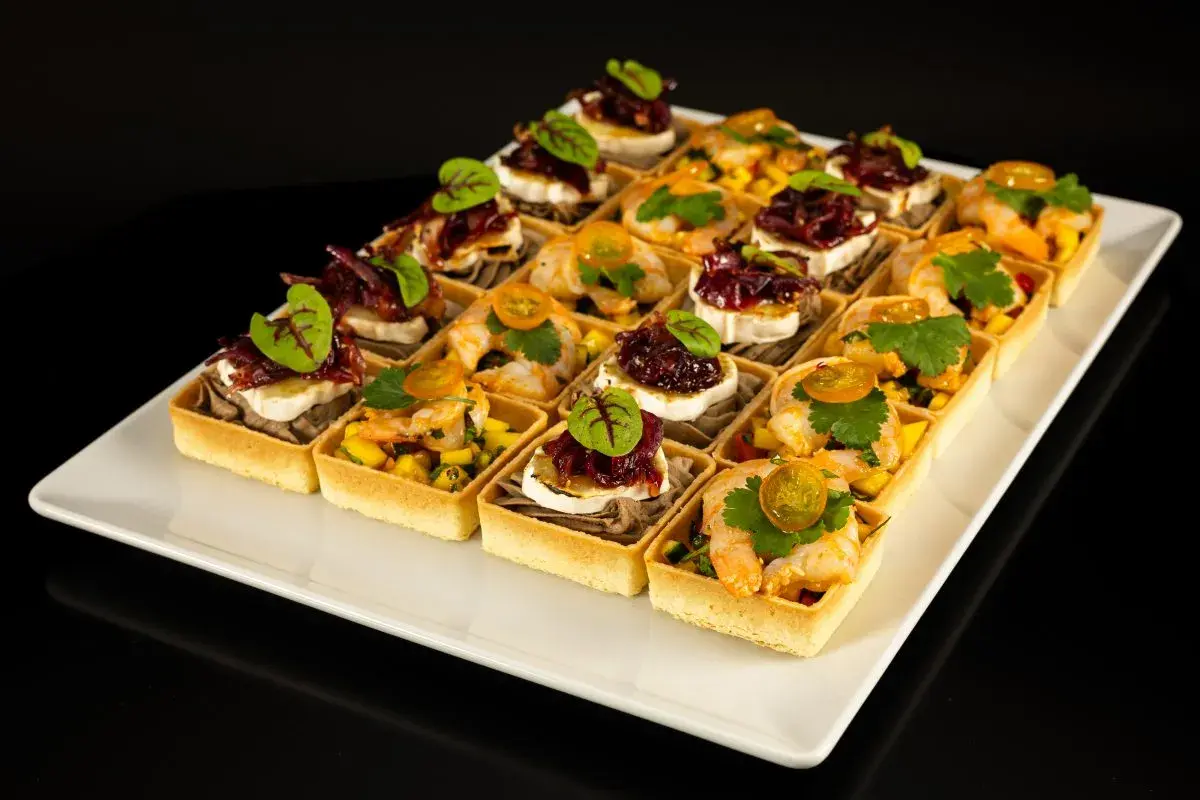Elegancki catering na konferencje: tartaletki z krewetkami i mango oraz z kozim serem i konfiturą z czerwonej cebuli.