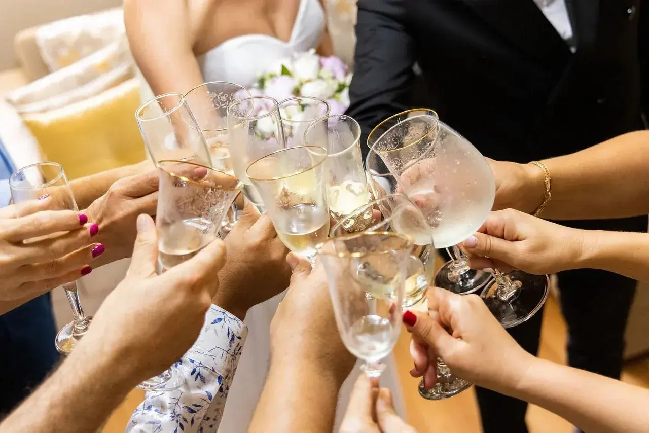 Radosny toast podczas polskiego ślubu. Dłonie trzymają kieliszki z szampanem, tworząc symbol jedności i świętowania.