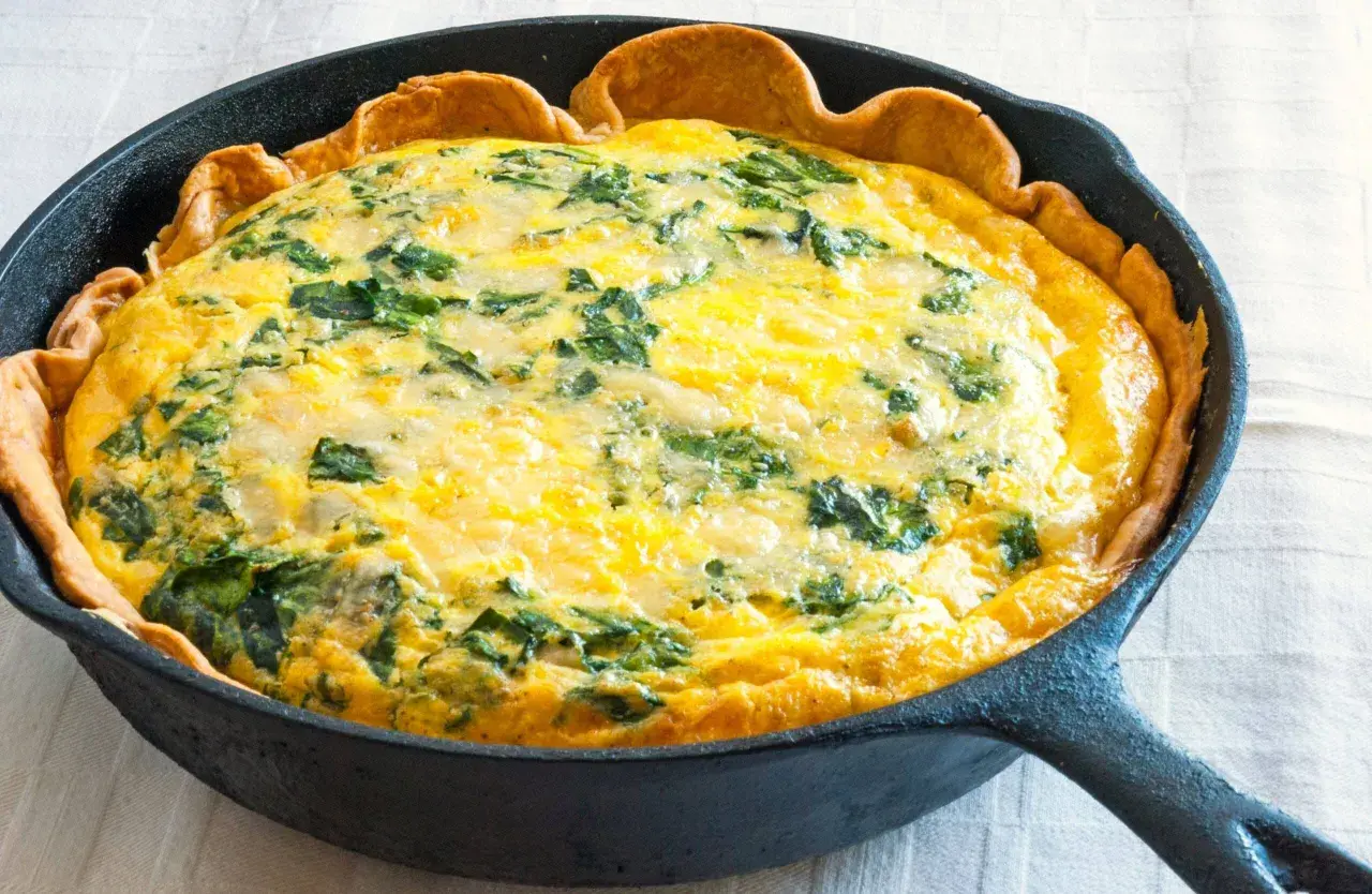 Quiche aux épinards dans une poêle en fonte. Une idée parfaite pour savoir que faire avec 3 jaunes d'œufs restants.