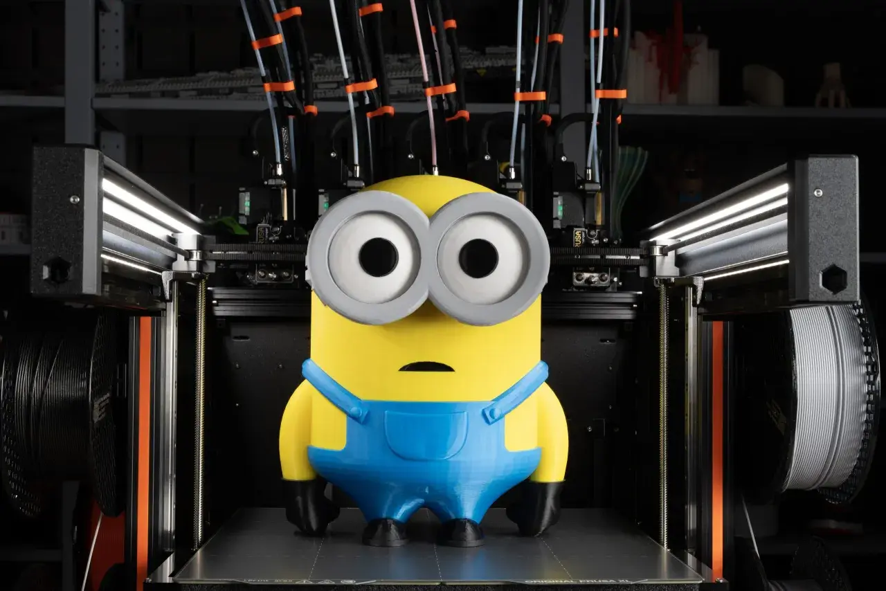 Minion wydrukowany na dobra drukarka 3d. Maszyna z wieloma głowicami i szpulami filamentu w tle.