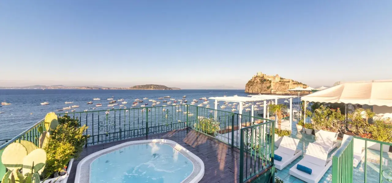 Terrazza con vasca idromassaggio e vista sul mare, barche e il Castello Aragonese. Un sogno al **Hotel Miramare e Castello Ischia**.