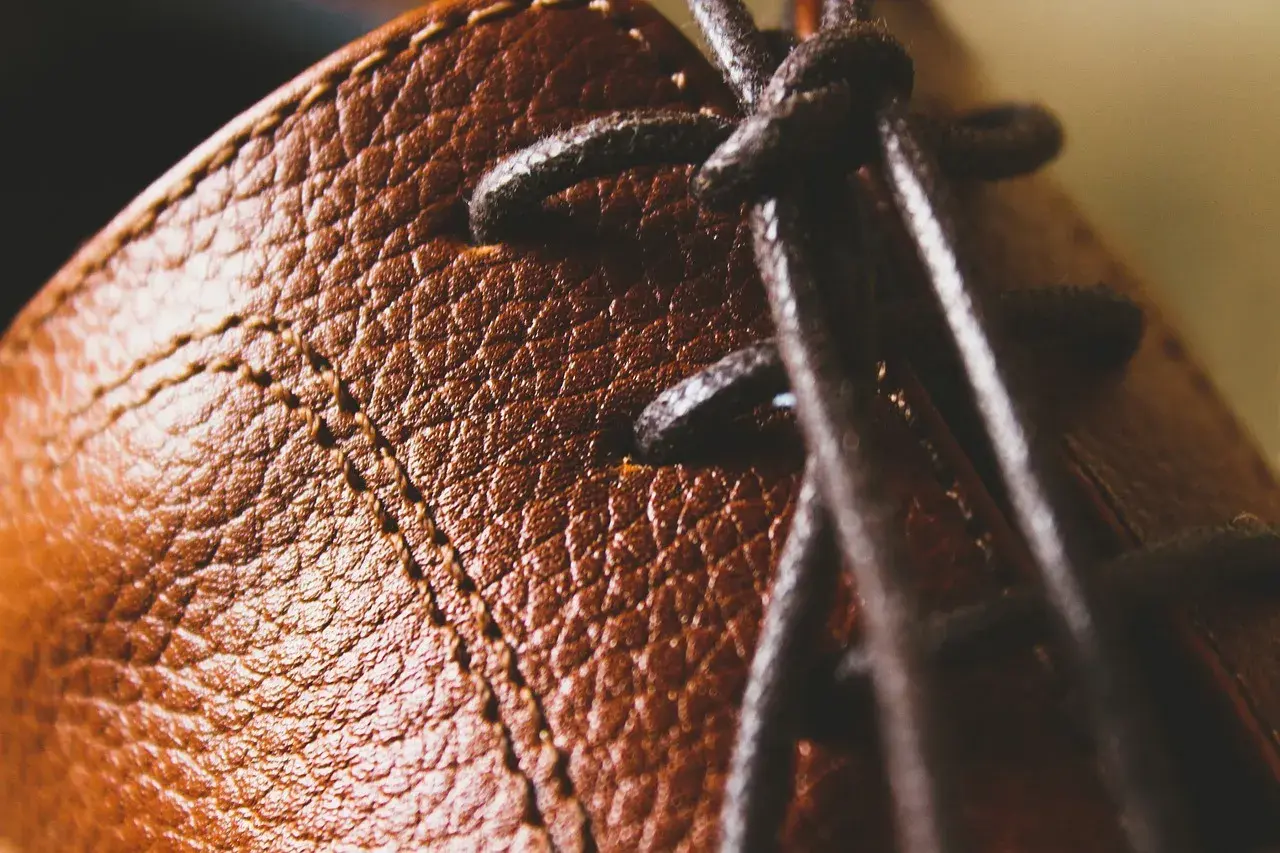 Gros plan sur le cuir texturé d'une chaussure marron, avec des lacets sombres. Un peu de cirage pour chaussures pourrait lui redonner tout son éclat.