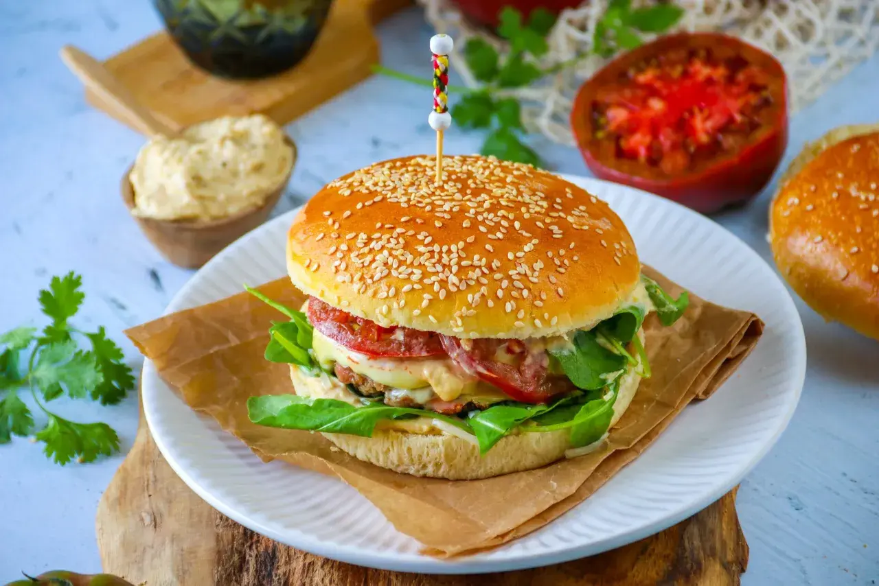 Un délicieux pain burger maison garni de viande, fromage fondant, tomates et roquette fraîche. Un vrai régal !