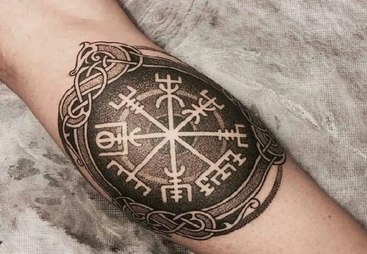 Tatuaż na ramieniu: kompas wikingów, symbol Vegvisir, otoczony skomplikowanymi nordyckimi wzorami.