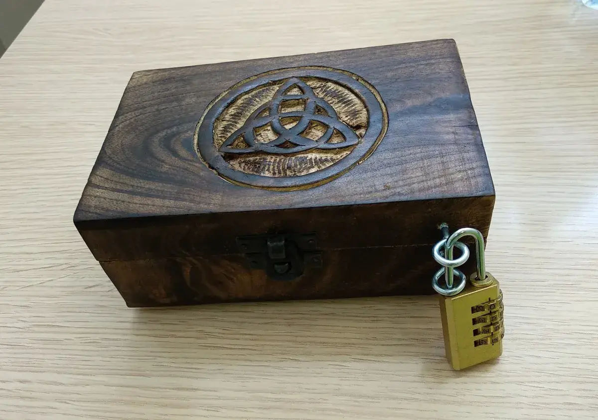 Caja de madera con símbolo celta y candado de combinación, lista para un escape room matematicas.