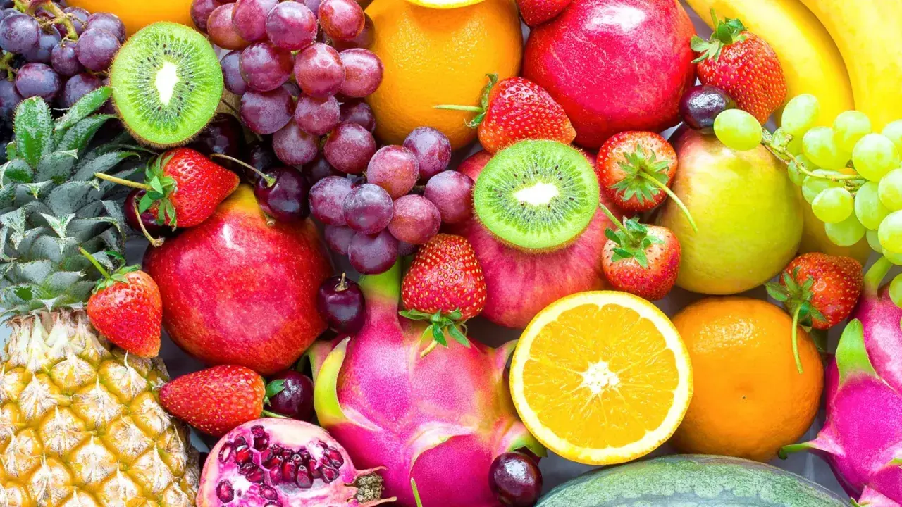 Un assortiment coloré de fruits frais : ananas, fraises, raisins, kiwis, pommes, oranges, bananes, poires, fruits du dragon et grenades. Une excellente source de fibre pour une alimentation saine.