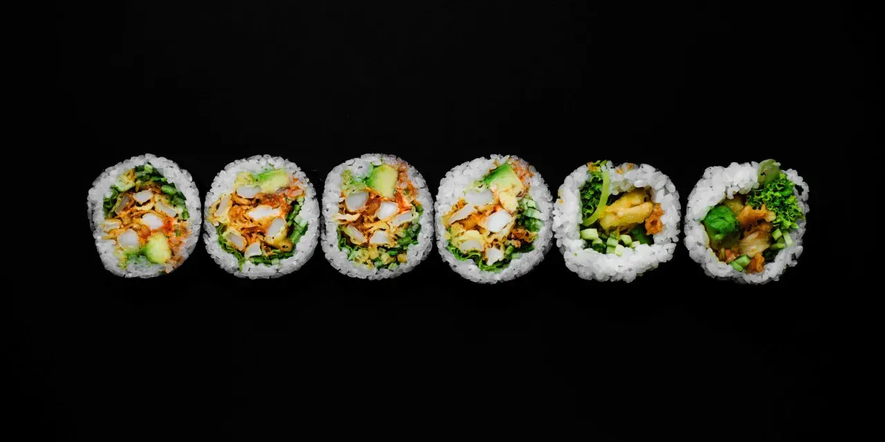 Sześć kawałków futomaki, czyli dużych rolek sushi, z awokado, warzywami i smażonymi kawałkami.