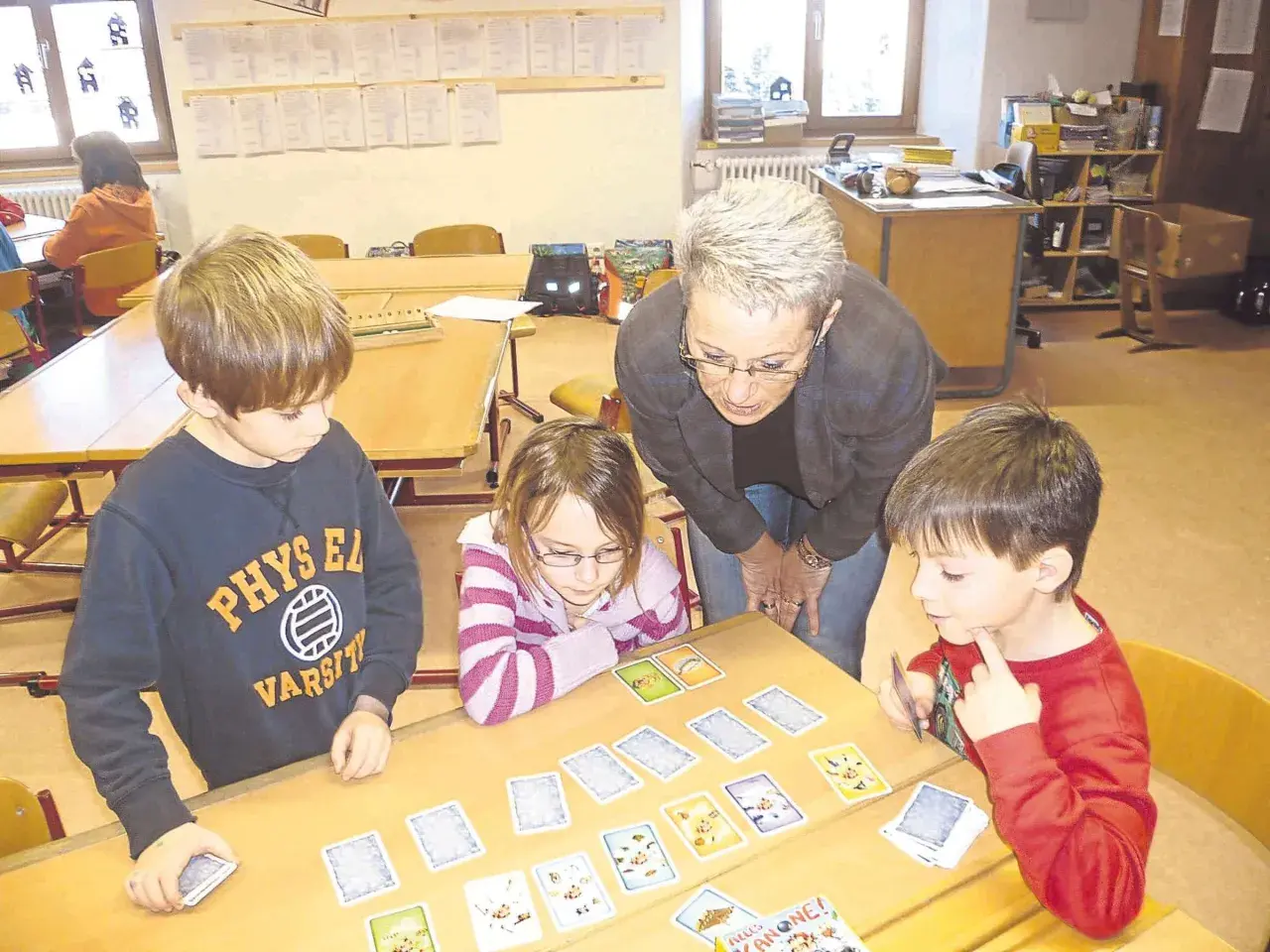 Lehrerin erklärt Kindern beim Projekttag Grundschule ein Kartenspiel.