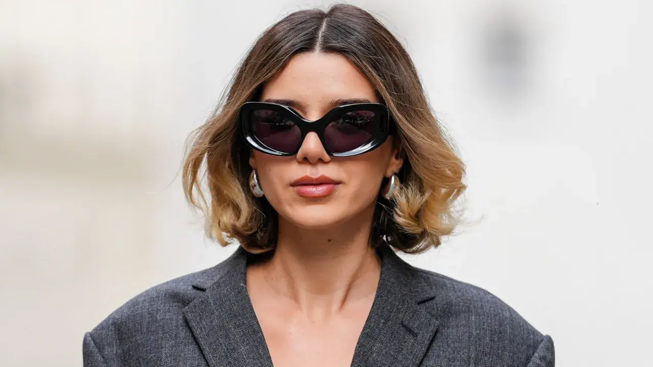 Mujer con gafas de sol y un moderno balayage pelo corto en tonos miel y castaño.