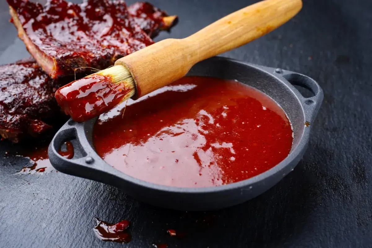 Pyszne żeberka w sosie bbq. Pędzelek zanurzony w sosie, gotowy do smarowania. Idealny sos bbq przepis.