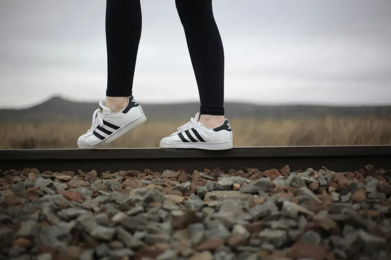 Białe adidasy Superstar to idealne buty do legginsów, świetnie wyglądają na tle torów kolejowych i krajobrazu.