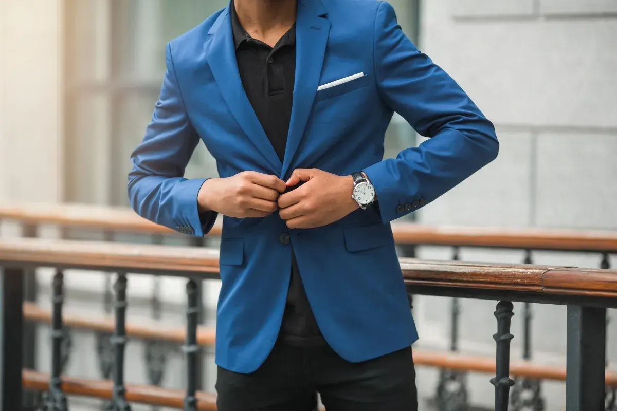 Mann im blauen Anzug und schwarzem Hemd, der seinen Anzug zuknöpft. Elegante Kleidung für einen besonderen Anlass.