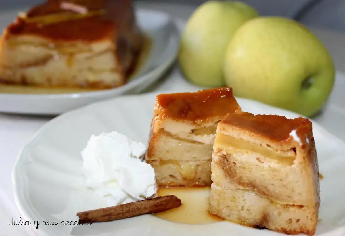 Delicioso pudin de manzana con caramelo, crema batida y canela. Dos porciones servidas en un plato blanco, con dos manzanas verdes al fondo.