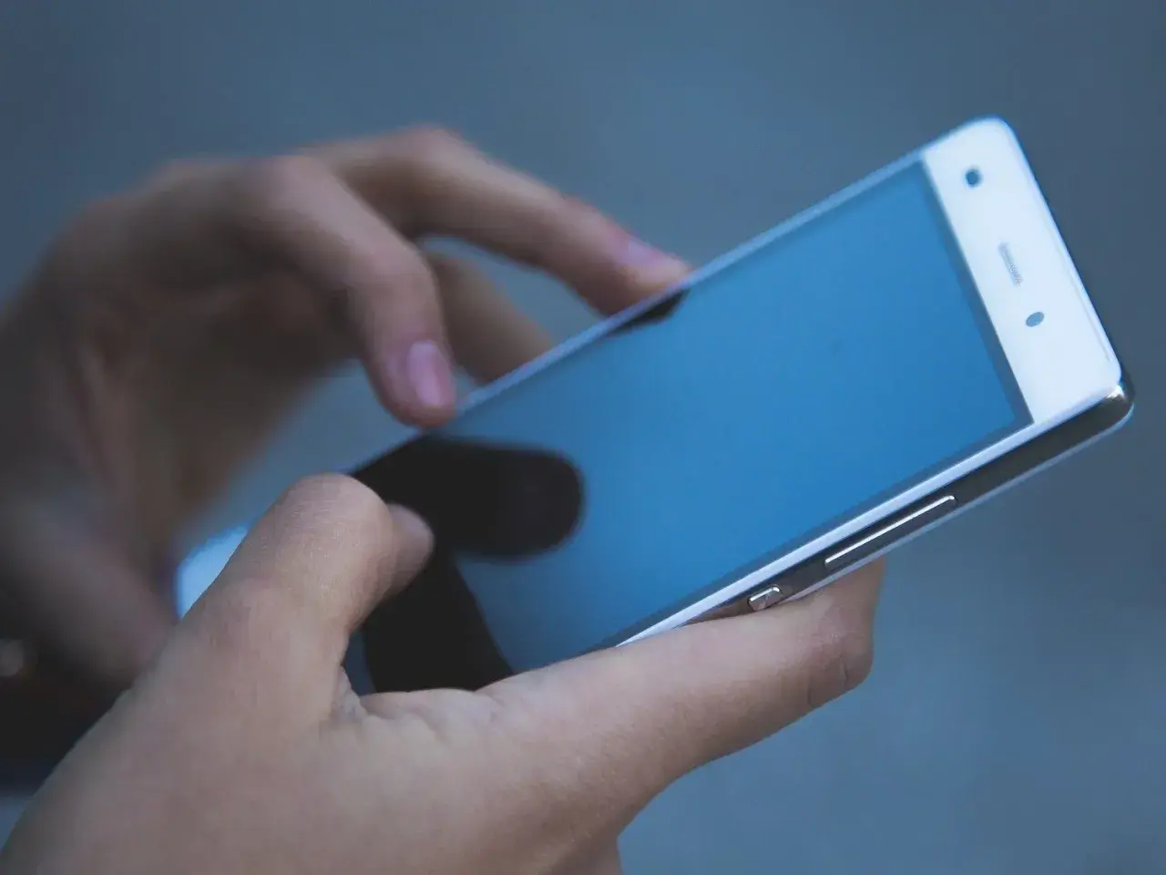 Dłonie trzymają telefon zmarłej osoby, przeglądając ostatnie wiadomości.