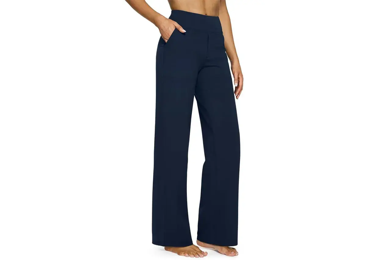 A person models navy blue yoga pants with a wide leg, perfect for hemming to achieve the ideal length for any activity.