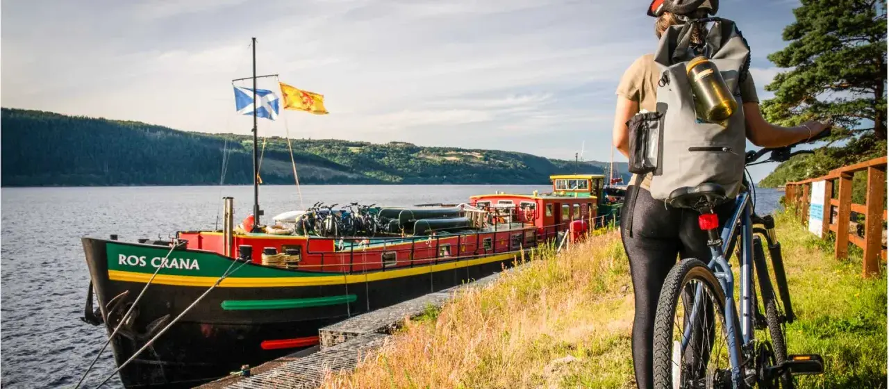 A cyclist pauses by a colorful barge loaded with bikes, ready for an adventure on the water.