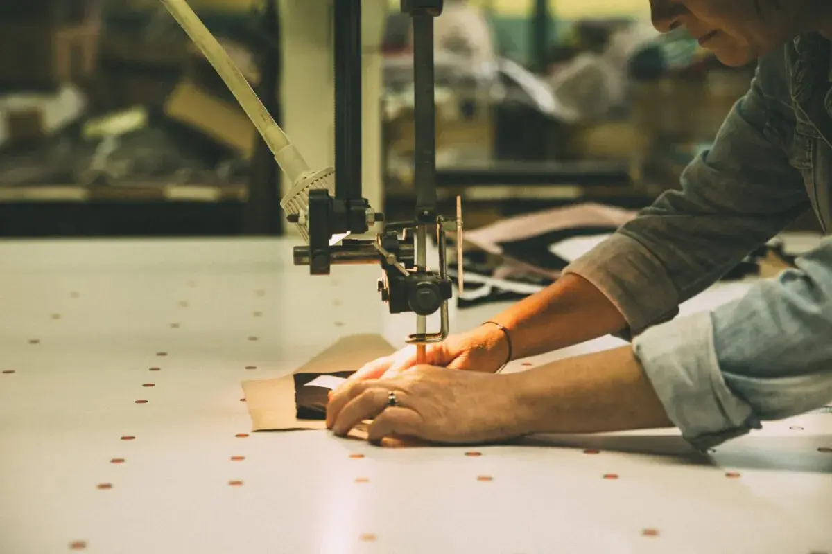 Mains guidant un tissu sous une machine à coudre, créant une pièce sans couture.