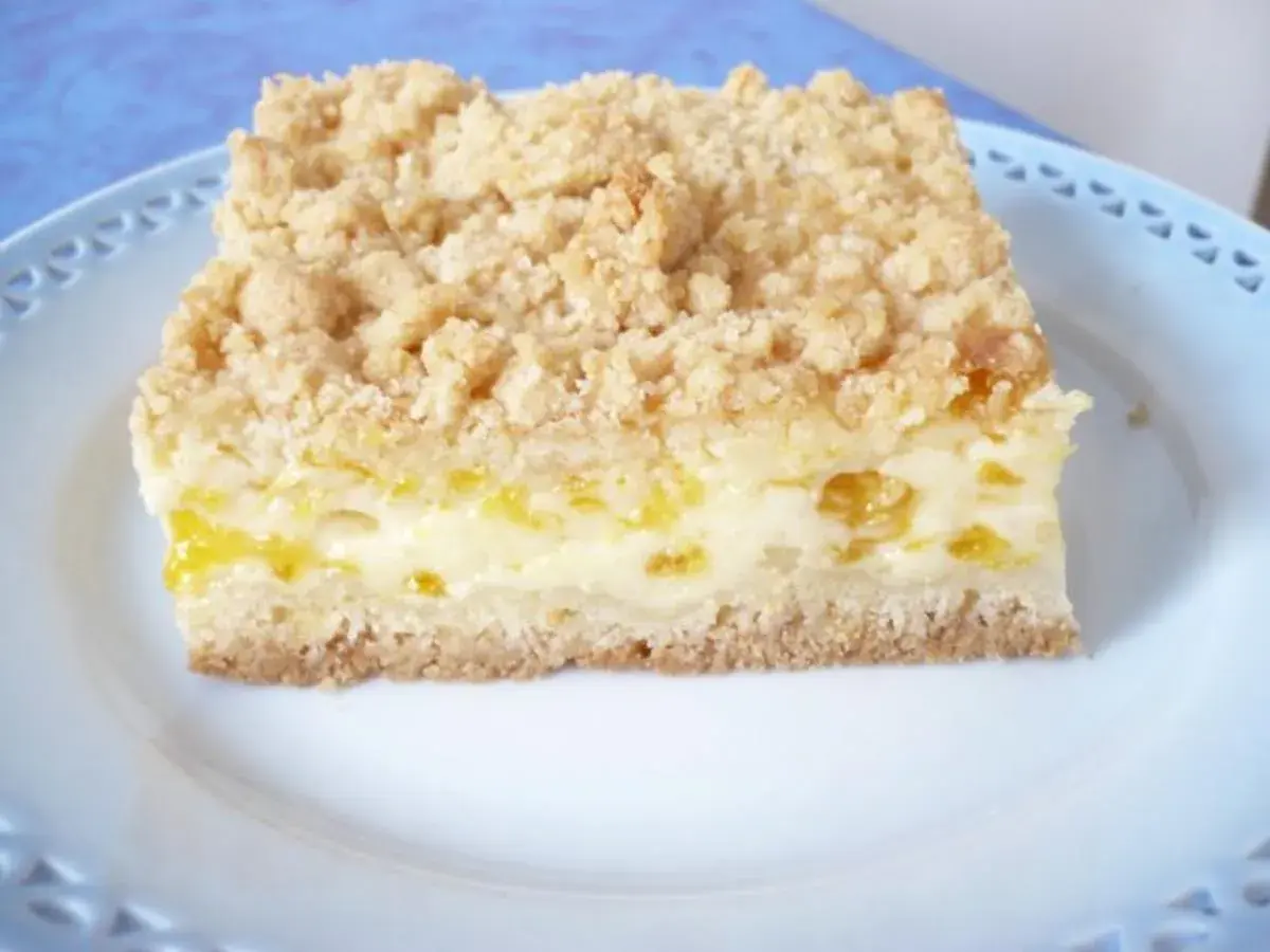 Ein Stück saftiger Mandarinenkuchen vom Blech mit Streuseln auf einem blauen Teller.