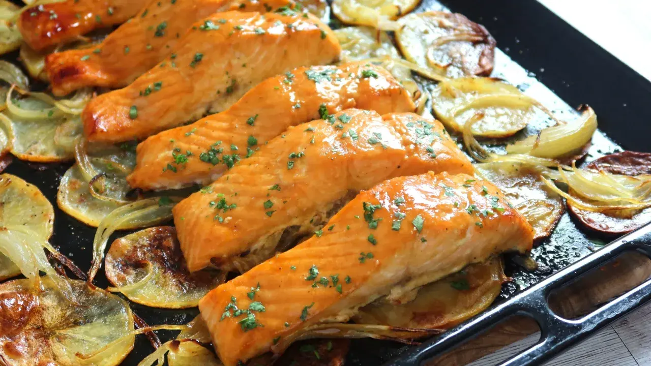 Filetes de salmón jugoso al horno con patatas y cebolla asadas.
