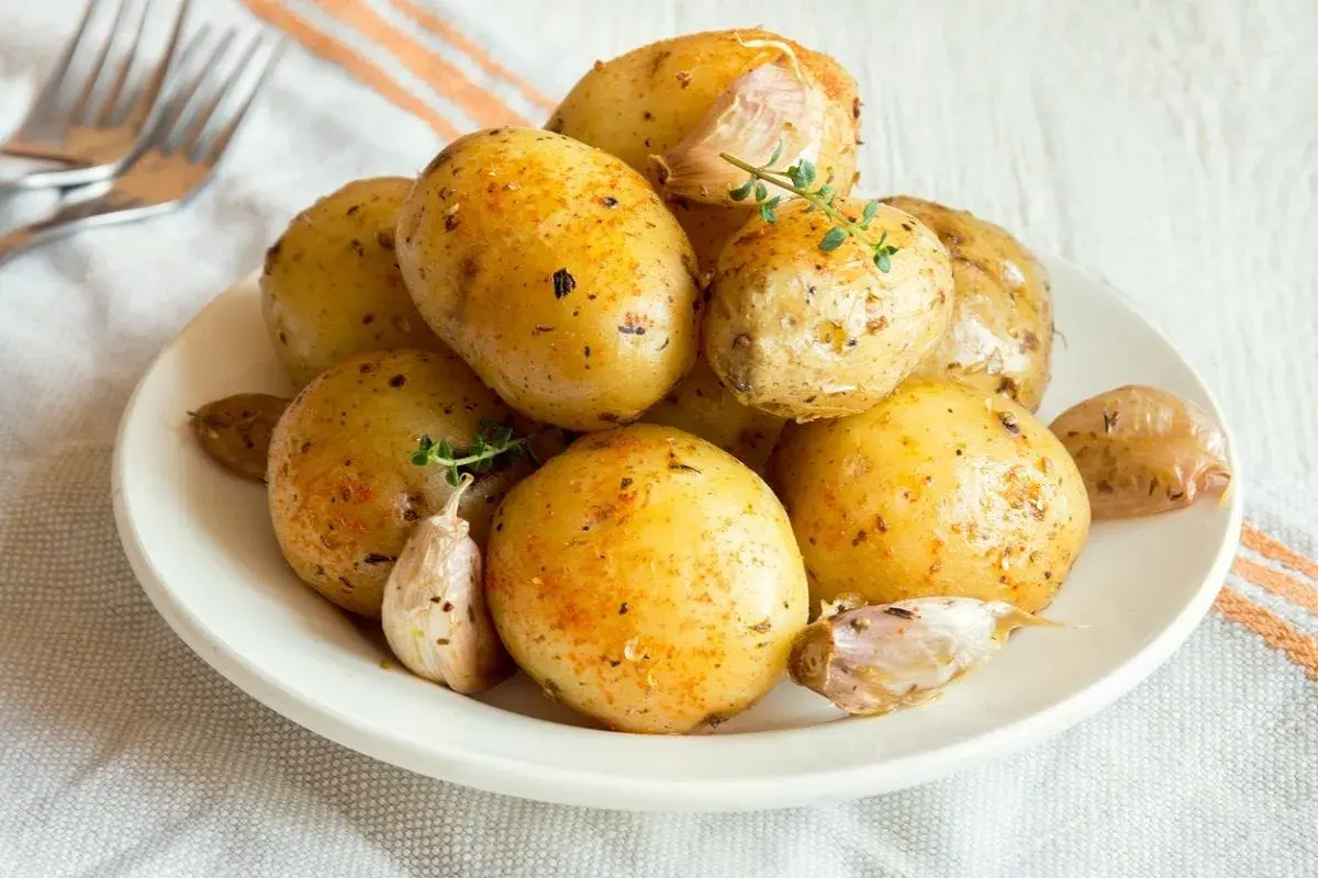 Patate al microonde in 3 minuti, condite con aglio e erbe aromatiche, pronte per essere gustate.