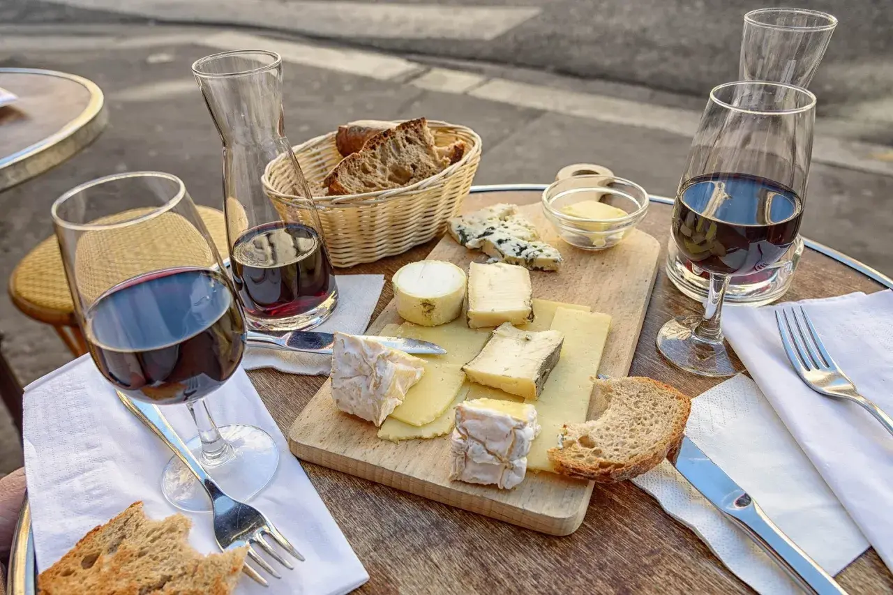 Assiette de fromages variés, pain croustillant et vin rouge, une dégustation parfaite pour accompagner un Saint-Émilion.