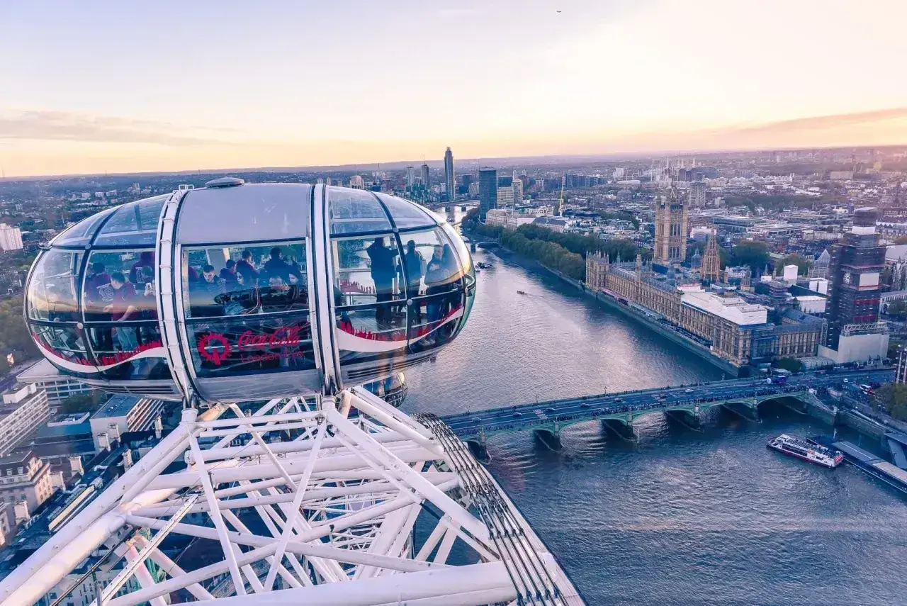 Widok z kapsuły London Eye na Tamizę i Parlament. Ludzie podziwiają panoramę Londynu o zachodzie słońca.