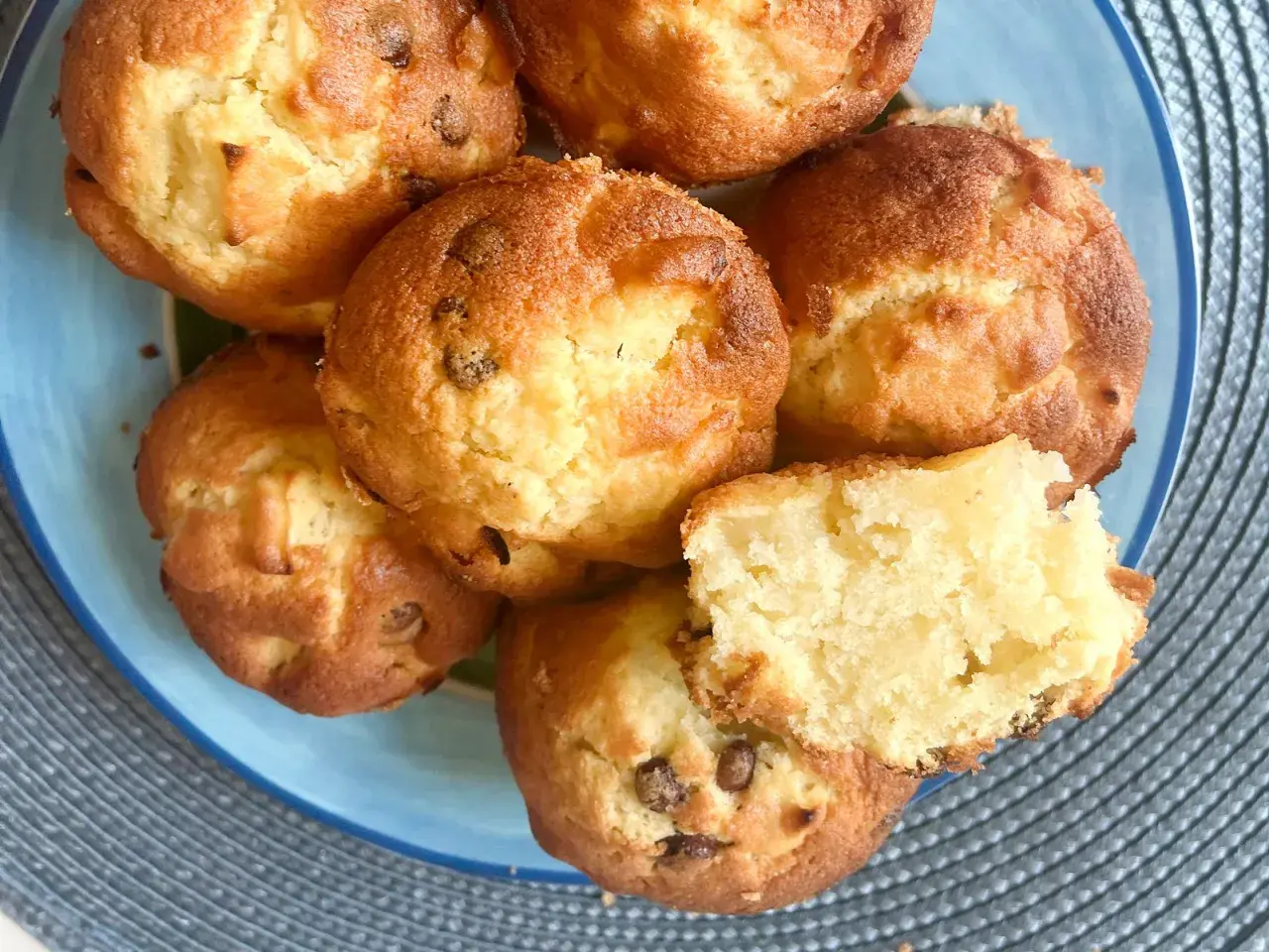 Saftige Apfelmus Muffins mit Schokostückchen auf einem blauen Teller. Einer ist aufgeschnitten und zeigt die lockere Textur.
