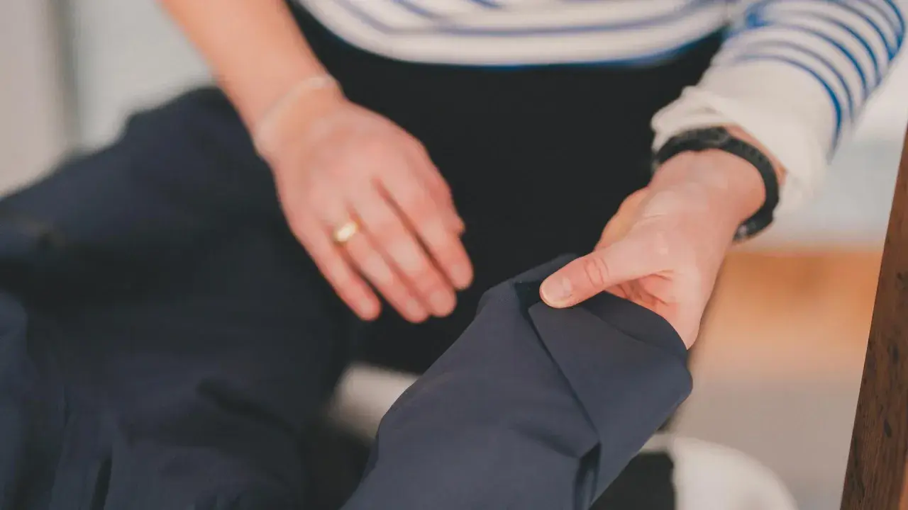 Dłonie przygotowują ciemną kurtkę do prania. Dowiedz się, jak prać Gore-Tex, by zachować jego właściwości.