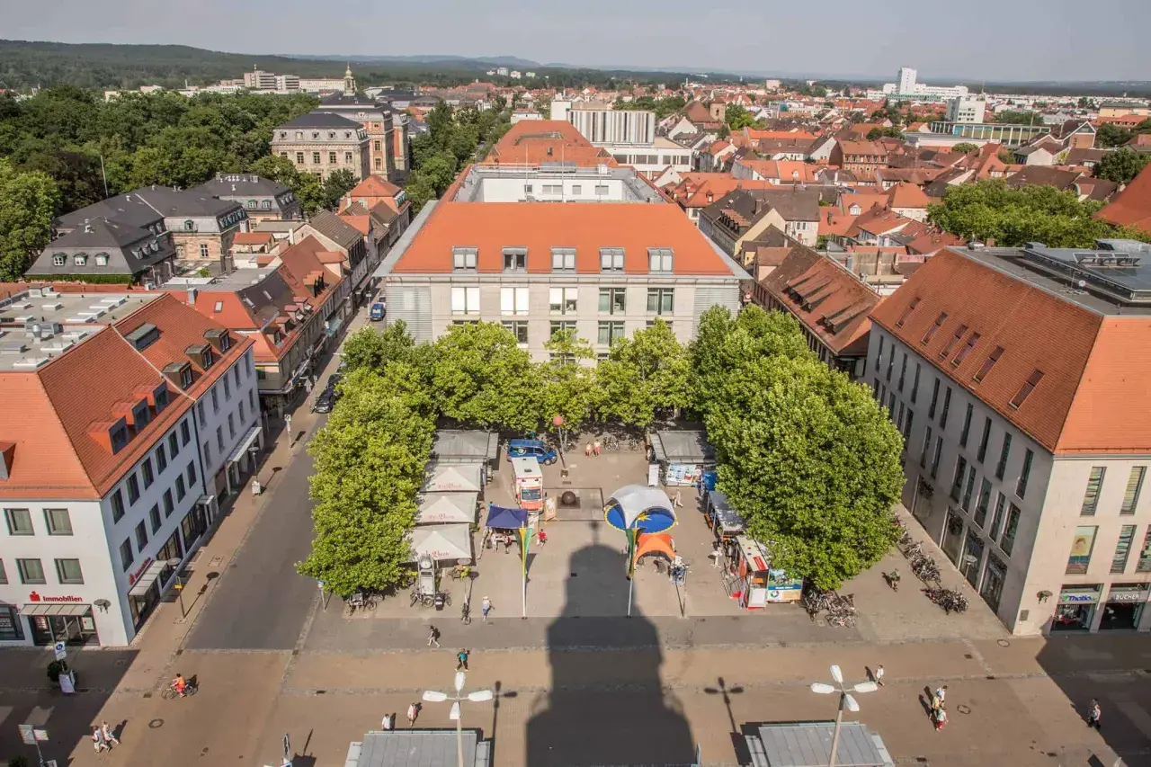 Marktplatz in Erlangen mit Ständen und Bäumen. Ein Schatten wirft sich über den Platz, vielleicht ein Geheimtipp für Fotografen.