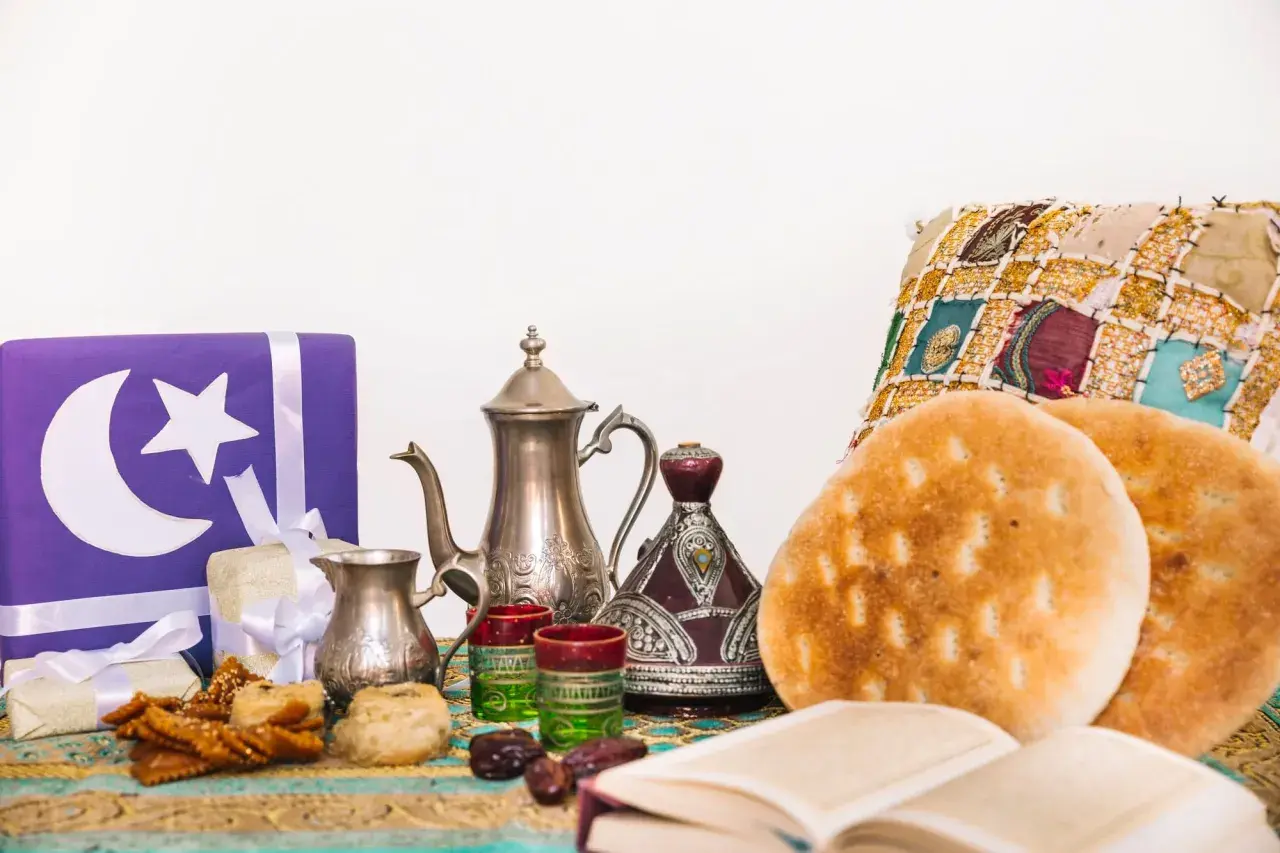 Przygotowania do iftaru: ozdobne prezenty, tradycyjny czajniczek, daktyle, pieczywo i książka.