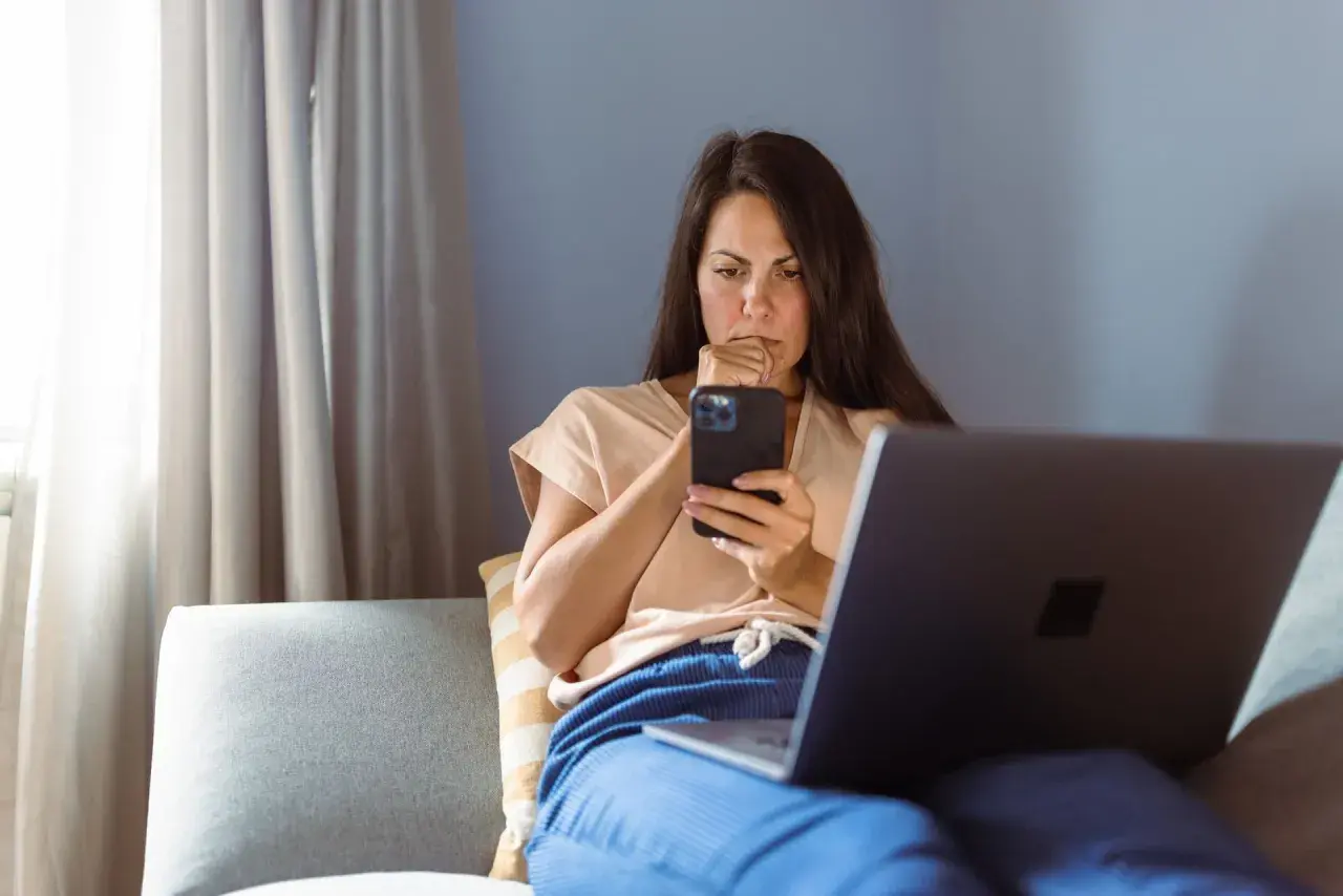 Besorgte Frau am Handy, die über eine neue Betrugsmasche Immobilien recherchiert.