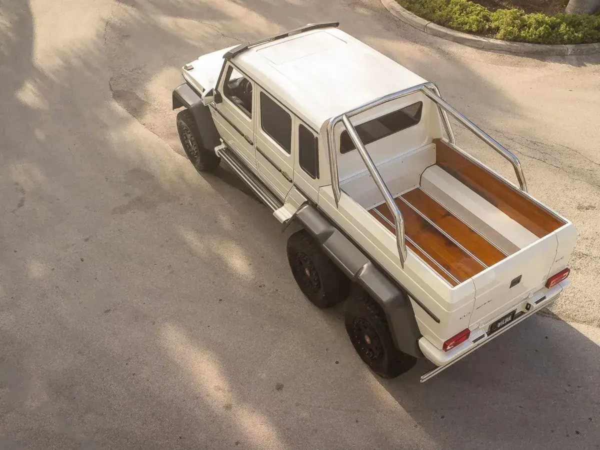Biały Mercedes 6x6 z drewnianą paką, gotowy na każdą przygodę.