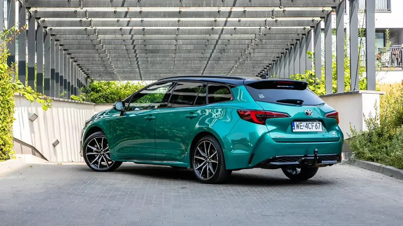 Zielona Toyota Corolla kombi z czarnym dachem, zaparkowana pod nowoczesną pergolą. Sprawdź atrakcyjną toyota corolla cena!
