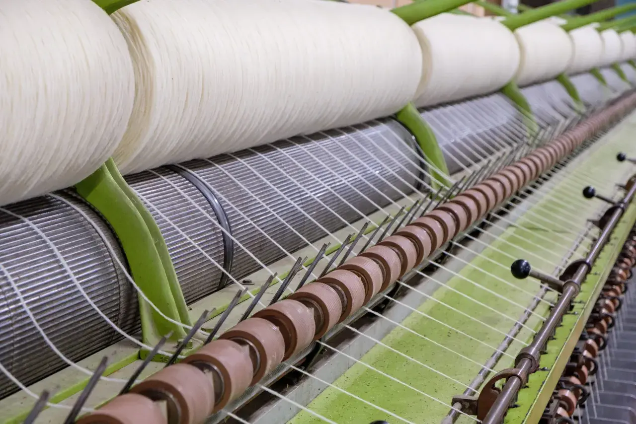 Gros rouleaux de fil blanc sur une machine de filature. Le processus de filature est en cours, transformant la matière première en fil.