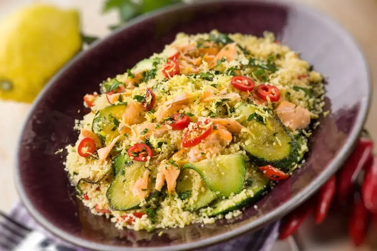 Un saporito cous cous con verdure, tonno e peperoncino, guarnito con scorza di limone e prezzemolo.