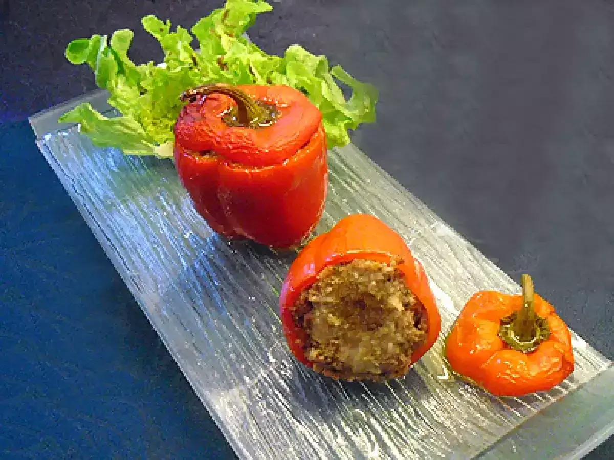 Poivrons farcis à la chair à saucisse, servis sur un plateau en verre avec une feuille de laitue.