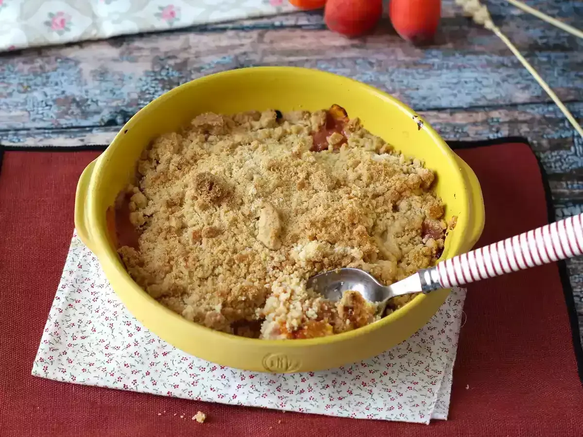 Ein goldbrauner Obst-Crumble im gelben Auflaufform, bereit zum Genießen. Dieses Crumble Rezept sieht köstlich aus!