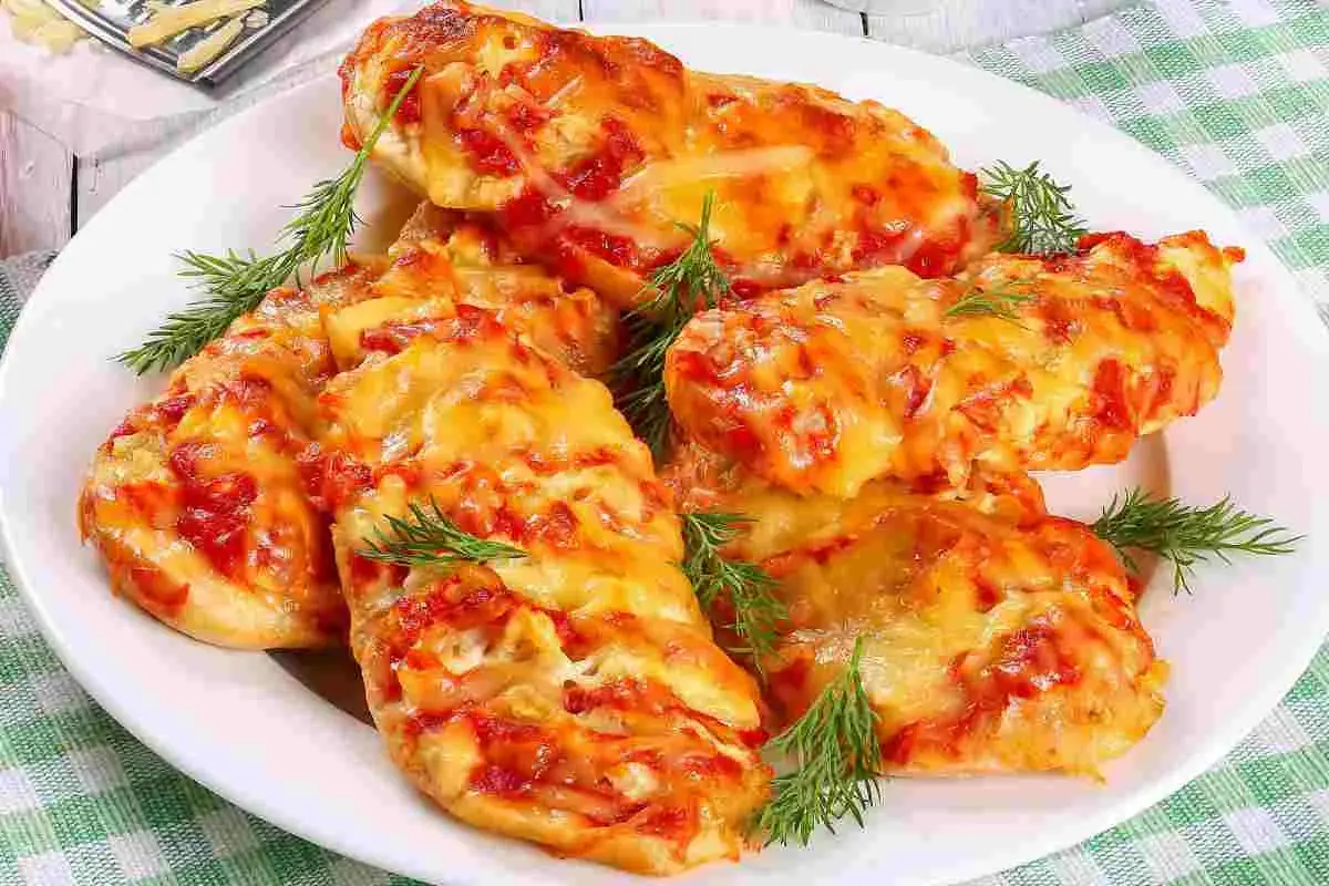Delizioso petto di pollo alla pizzaiola, cotto al forno con pomodoro e formaggio filante, guarnito con aneto fresco.