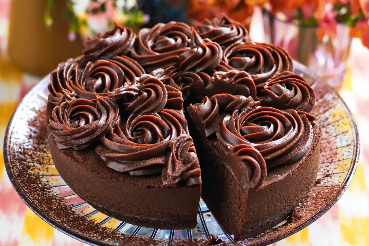 Una deliziosa torta al cioccolato, ricoperta da rosette di crema al cioccolato, con una fetta mancante che invita a un assaggio goloso.