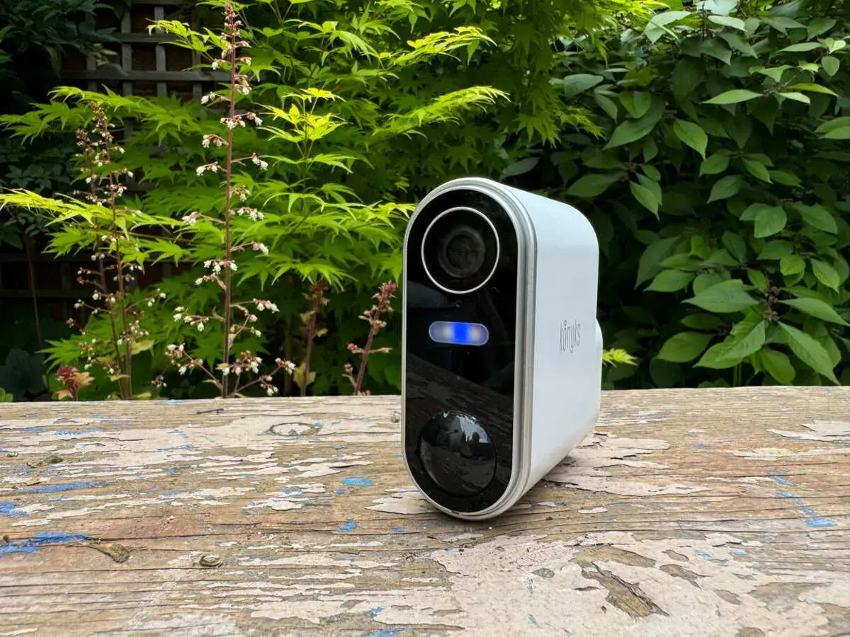 Une caméra de surveillance blanche avec une lumière bleue allumée, posée sur un banc en bois. Un moyen simple pour savoir si une caméra fonctionne.
