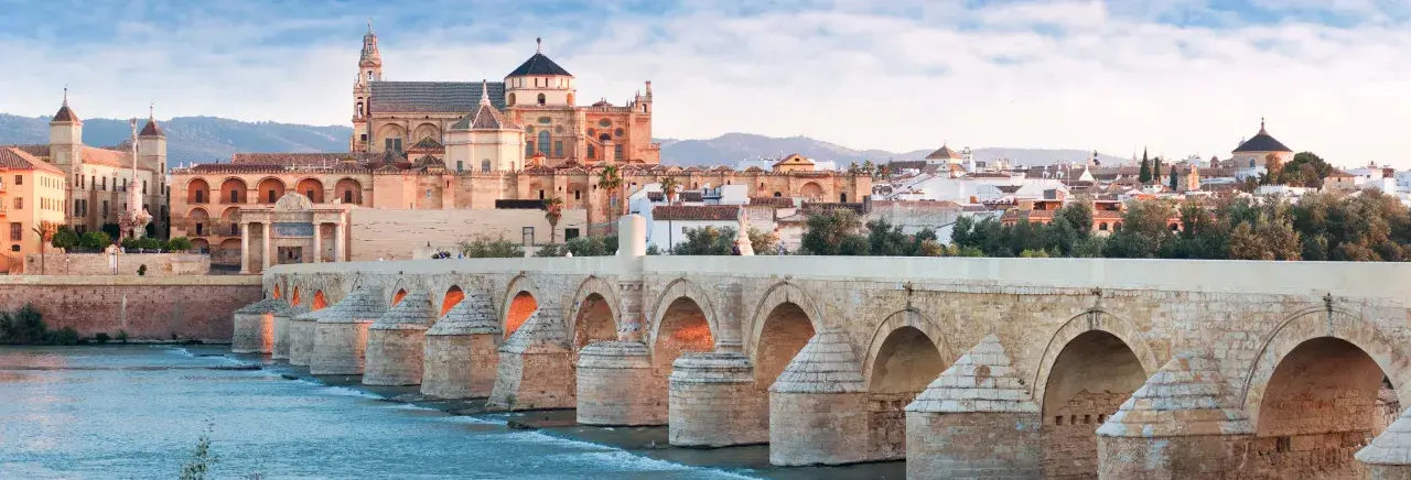 El Puente Romano cruza el Guadalquivir hacia la impresionante mezquita catedral de Córdoba, bañada por la luz del amanecer.