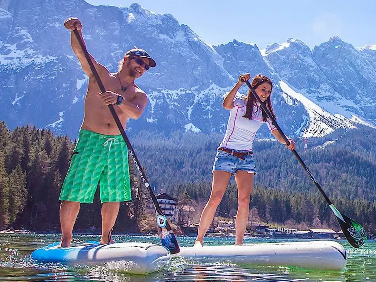Ein Mann und eine Frau genießen das Stand Up Paddle Boarding auf einem Bergsee.