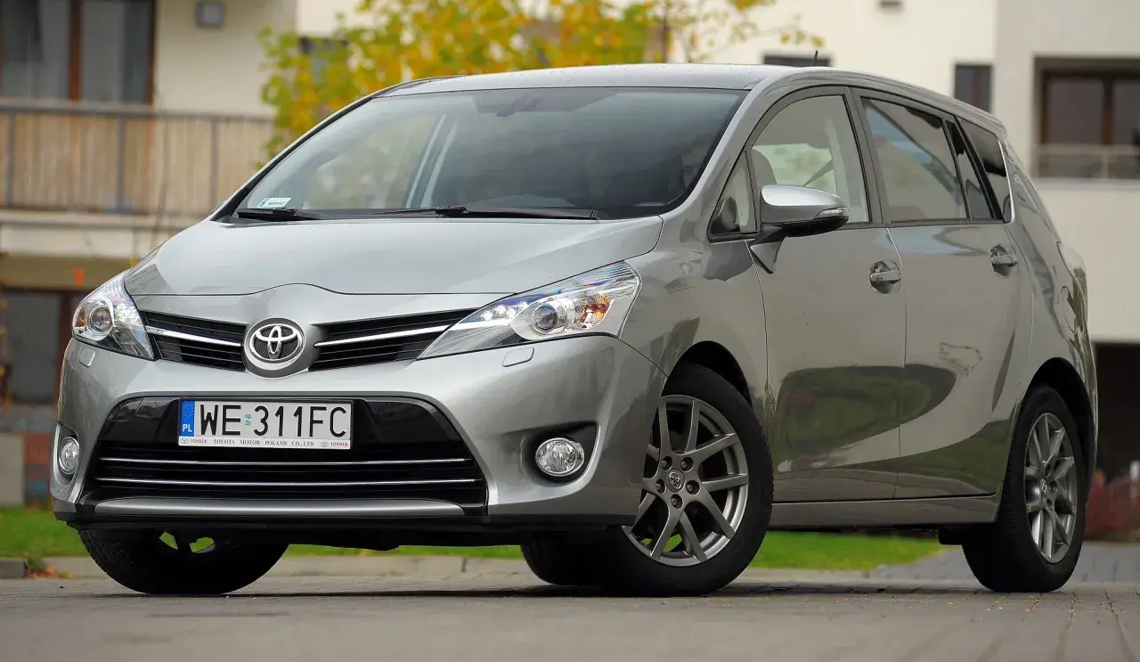 Srebrna Toyota Verso 1.8 benzyna zaparkowana przed budynkiem.