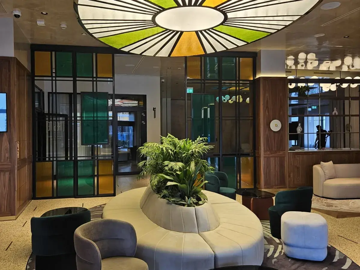 Nowoczesne wnętrze z designerską sofą i roślinnością. Kolorowe witraże i okrągły plafon tworzą niepowtarzalny klimat w grand hotelu Wrocław.
