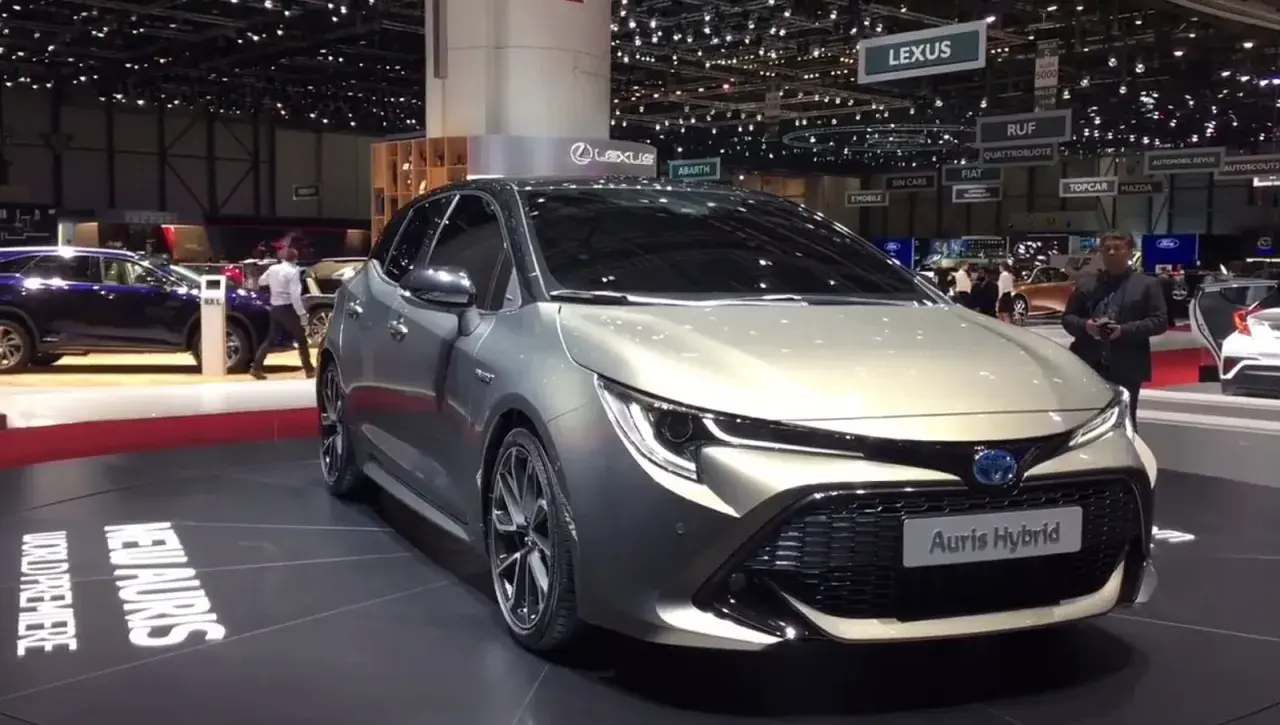 Elegancki, srebrny Auris Hybrid prezentowany na targach motoryzacyjnych. Na podłodze widoczny napis "NEW AURIS WORLD PREMIERE".