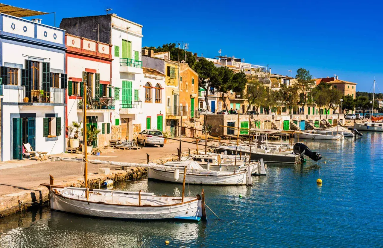 Bunte Häuserfront am Hafen, Boote im Wasser – ein idyllischer Urlaub auf Mallorca.